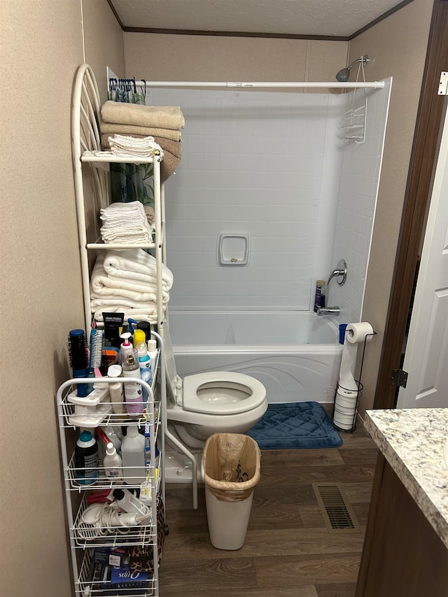 full bathroom with vanity, shower / washtub combination, hardwood / wood-style flooring, toilet, and a textured ceiling