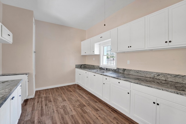 kitchen with dark stone countertops, white cabinets, dark hardwood / wood-style floors, and sink