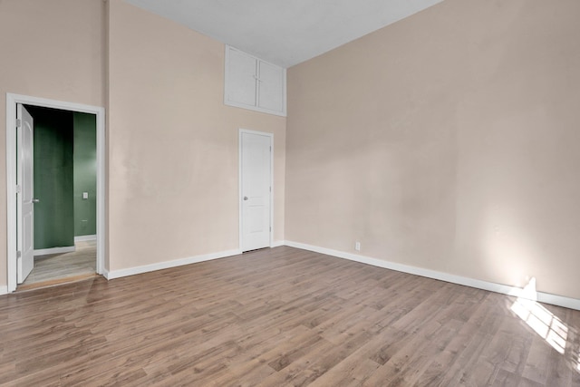 unfurnished room featuring a high ceiling and hardwood / wood-style floors