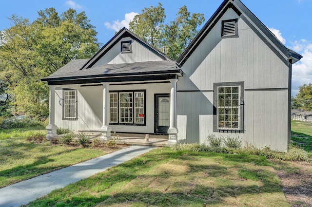 rear view of property featuring a porch and a yard