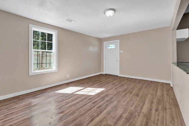 spare room featuring light wood-type flooring and a textured ceiling