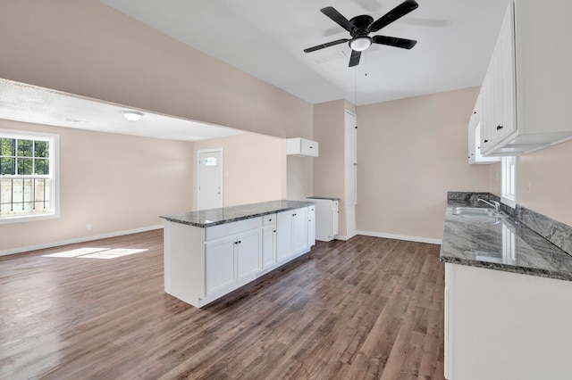 kitchen featuring ceiling fan, dark stone counters, sink, dark hardwood / wood-style floors, and white cabinets