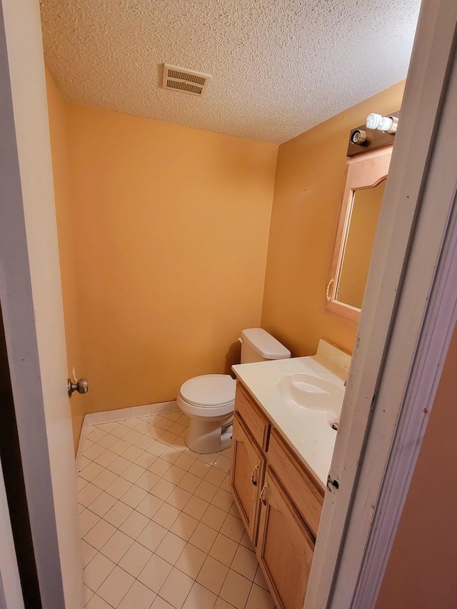 bathroom with tile patterned flooring, a textured ceiling, vanity, and toilet