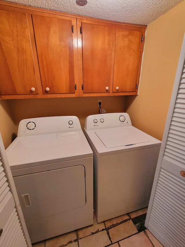 laundry area featuring cabinets, washing machine and clothes dryer, and a textured ceiling