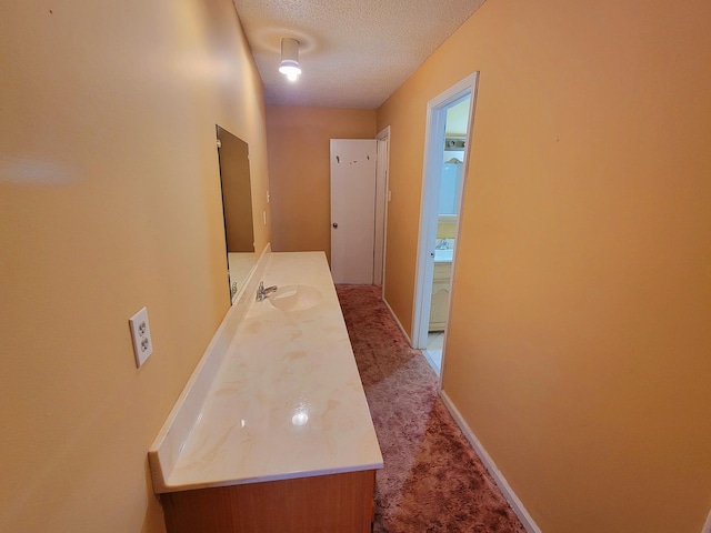 hall with light carpet, sink, and a textured ceiling