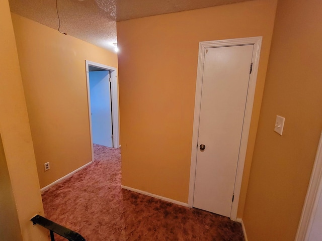 hall with carpet floors and a textured ceiling