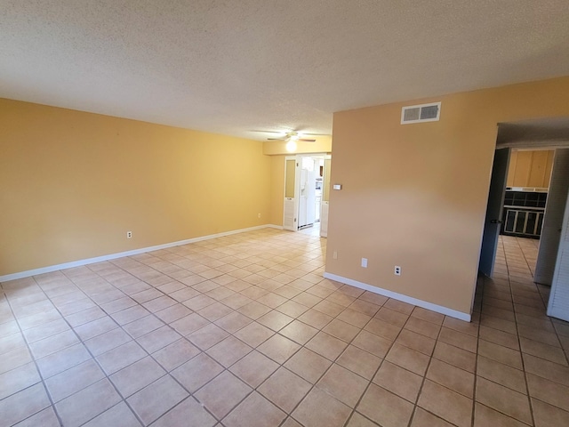 tiled empty room featuring a textured ceiling