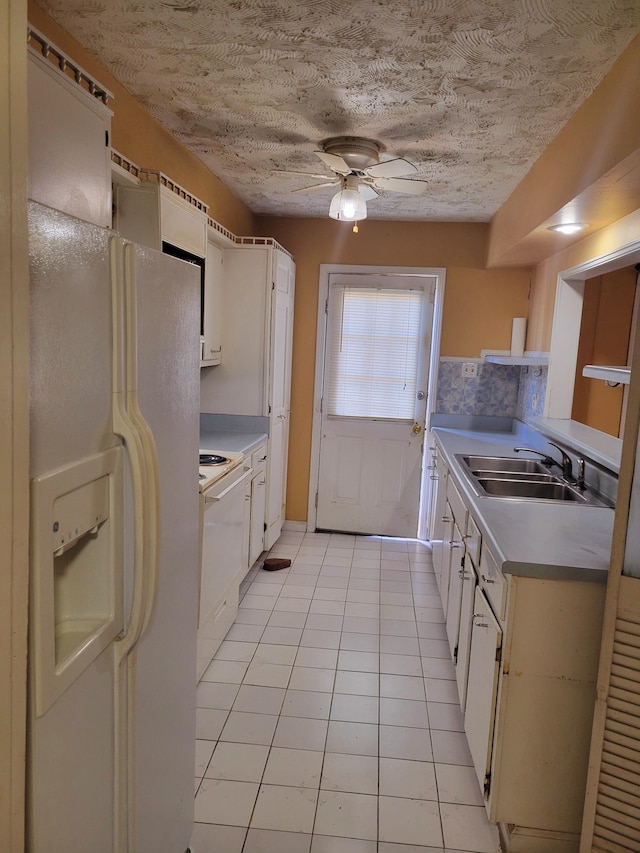 kitchen featuring white appliances, sink, light tile patterned floors, and white cabinets