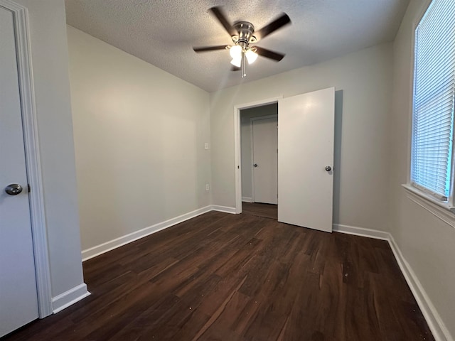 unfurnished bedroom with dark wood-type flooring, a textured ceiling, and ceiling fan