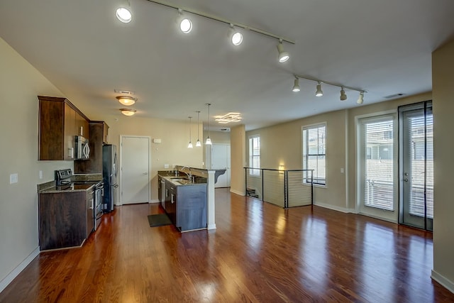 kitchen featuring stainless steel appliances, track lighting, pendant lighting, and dark hardwood / wood-style floors