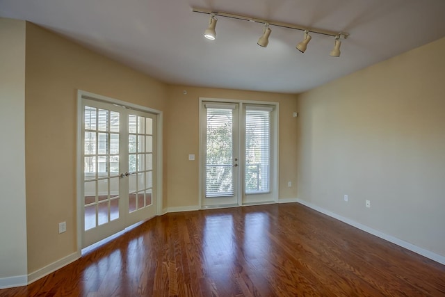 empty room with french doors, rail lighting, and hardwood / wood-style floors