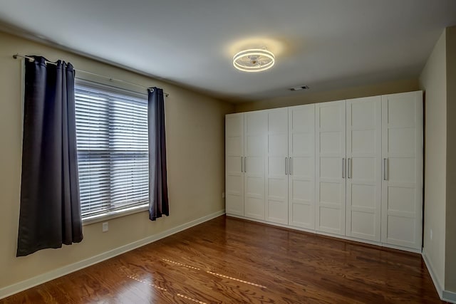 unfurnished bedroom featuring dark wood-type flooring and a closet