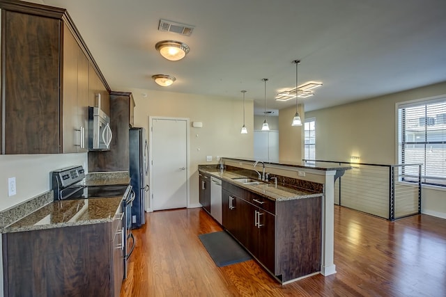 kitchen featuring pendant lighting, dark wood-type flooring, stainless steel appliances, and dark stone countertops