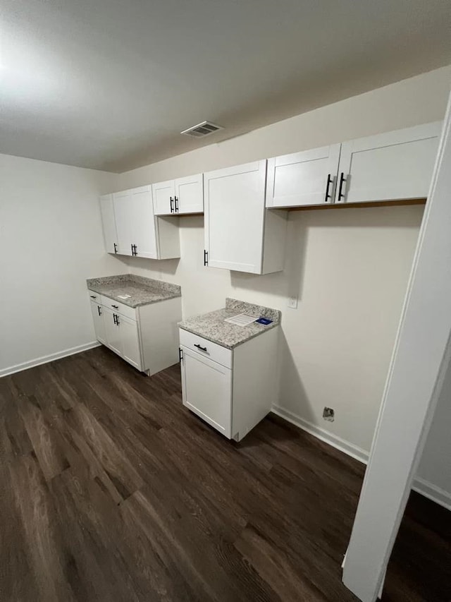 kitchen featuring white cabinets, light stone countertops, and dark hardwood / wood-style flooring