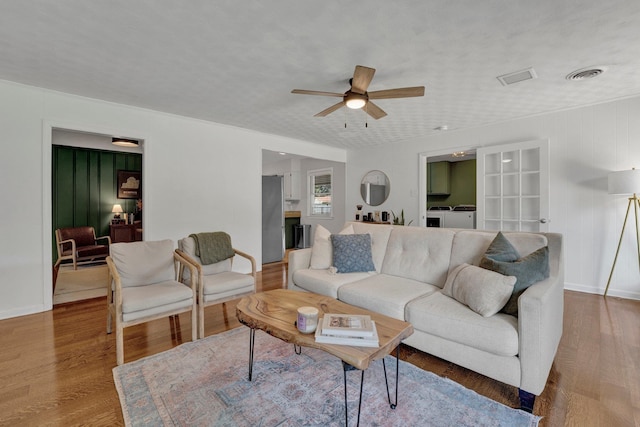 living room featuring ceiling fan, washing machine and clothes dryer, hardwood / wood-style floors, and a textured ceiling