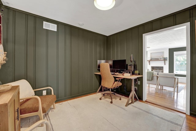 office area featuring a fireplace and light hardwood / wood-style floors