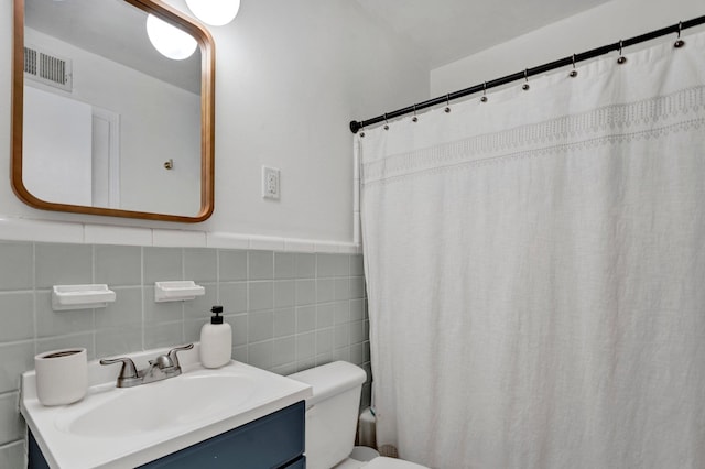 bathroom with toilet, tile walls, vanity, and a shower with curtain