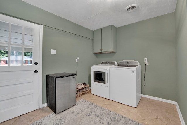 washroom featuring cabinets, light tile patterned flooring, washer and dryer, and a textured ceiling