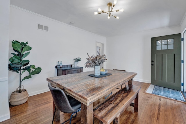 dining room featuring wood-type flooring, a notable chandelier, and crown molding