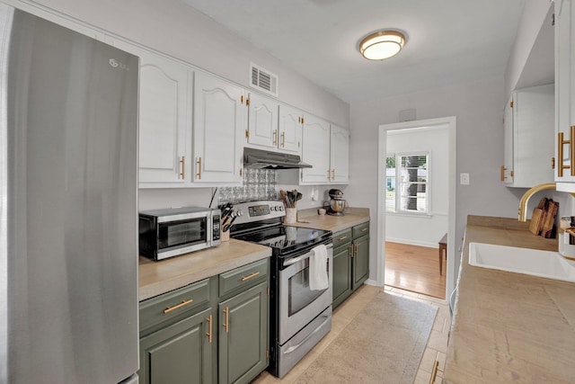 kitchen with sink, stainless steel appliances, light tile patterned floors, and white cabinetry