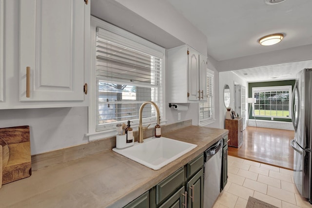 kitchen with a healthy amount of sunlight, white cabinetry, sink, and stainless steel appliances