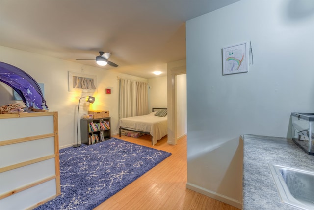 bedroom featuring ceiling fan, sink, and wood-type flooring