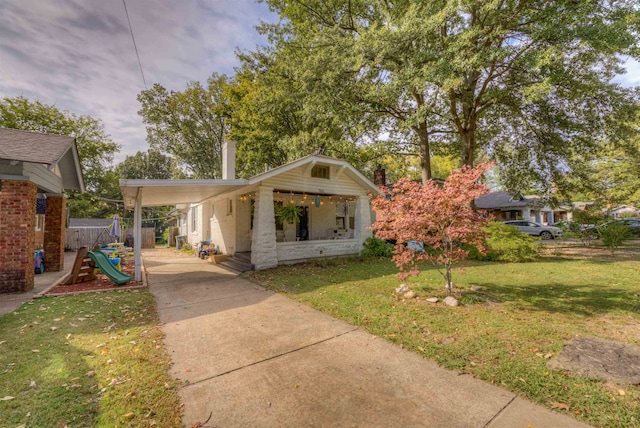 view of front of home featuring a playground, a carport, and a front yard