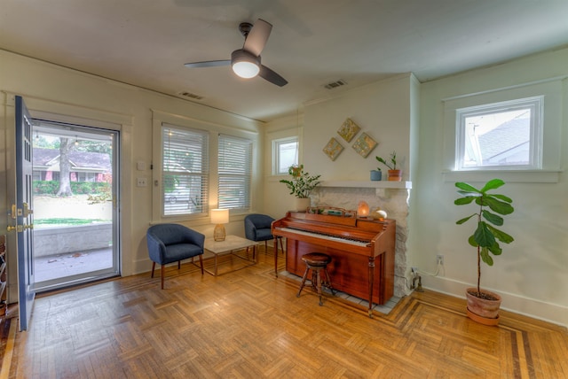 sitting room with plenty of natural light, parquet flooring, and ceiling fan