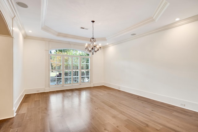 unfurnished dining area with light wood-type flooring, a raised ceiling, and ornamental molding