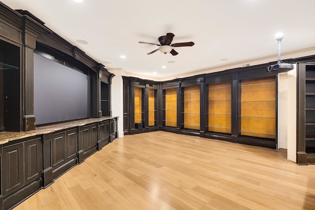 home theater with crown molding, light wood-type flooring, and ceiling fan