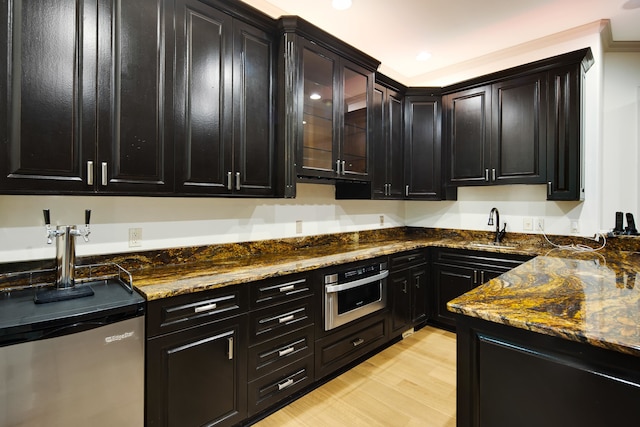 kitchen with sink, stainless steel appliances, light hardwood / wood-style floors, and dark stone counters