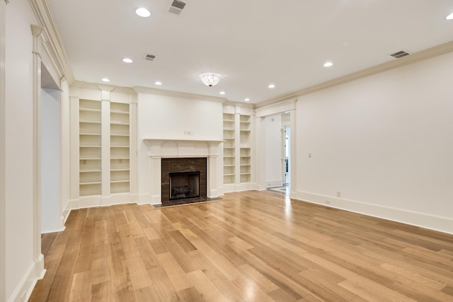 unfurnished living room with ornamental molding, a fireplace, built in shelves, and light hardwood / wood-style flooring