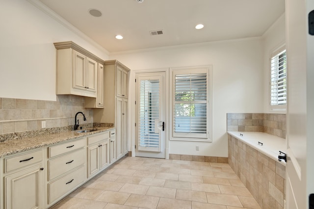 kitchen featuring light stone countertops, ornamental molding, sink, and a wealth of natural light