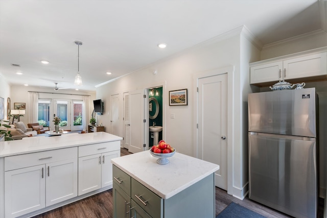 kitchen featuring stainless steel refrigerator, decorative light fixtures, a center island, and white cabinetry