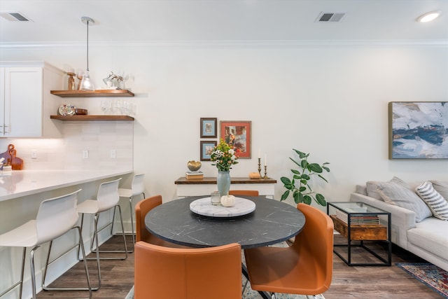 dining space with ornamental molding and dark hardwood / wood-style floors