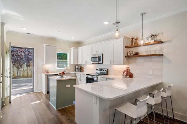 kitchen featuring kitchen peninsula, hanging light fixtures, appliances with stainless steel finishes, and white cabinetry