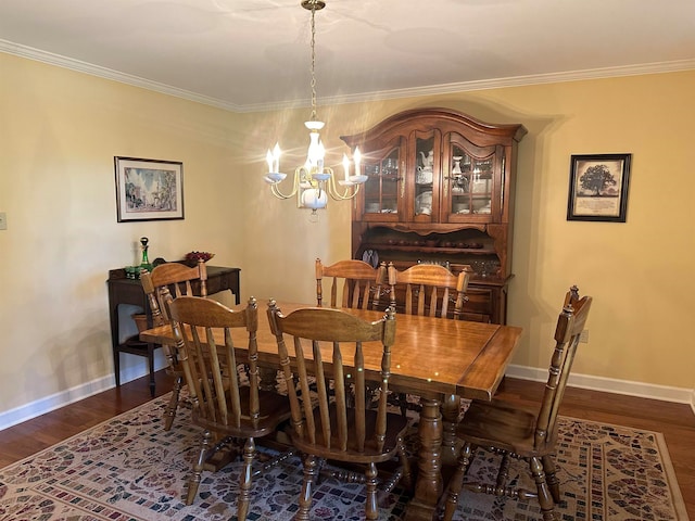 dining room featuring dark wood-type flooring, crown molding, and a chandelier