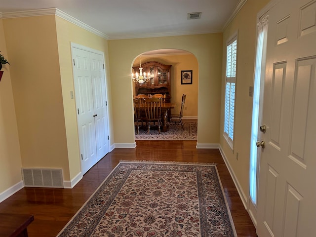 foyer with crown molding, dark hardwood / wood-style flooring, and a chandelier