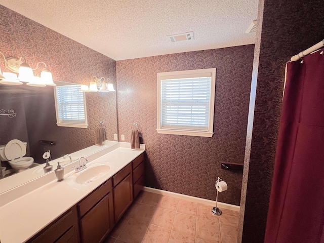 bathroom with tile patterned flooring, vanity, toilet, and a textured ceiling