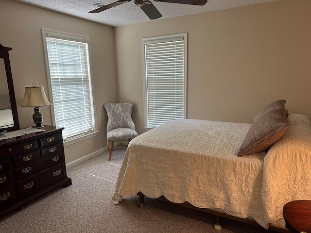 carpeted bedroom with multiple windows, ceiling fan, and a textured ceiling