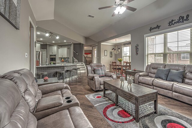 living room with dark hardwood / wood-style flooring, vaulted ceiling, and ceiling fan with notable chandelier