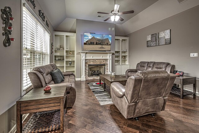 living room featuring a stone fireplace, ceiling fan, dark hardwood / wood-style flooring, built in features, and lofted ceiling