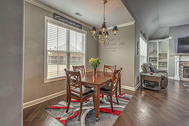 dining room with a notable chandelier, ornamental molding, dark hardwood / wood-style floors, a fireplace, and built in shelves