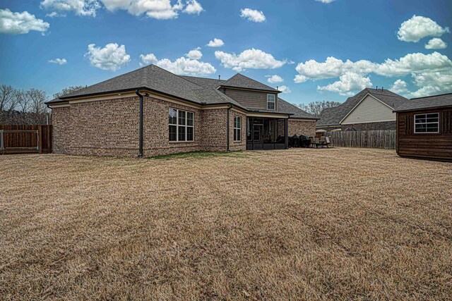 back of property with a lawn and a sunroom