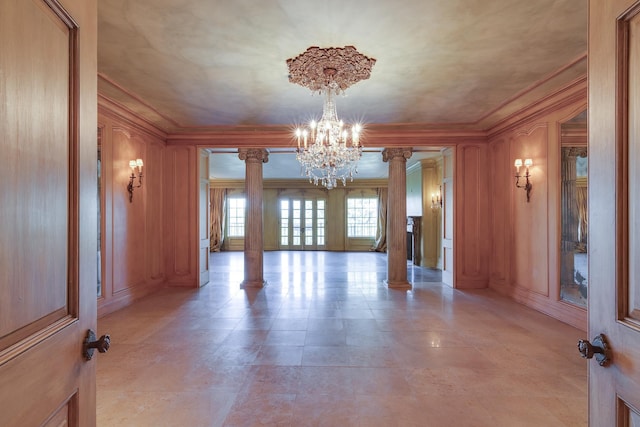 empty room featuring ornate columns, an inviting chandelier, and crown molding