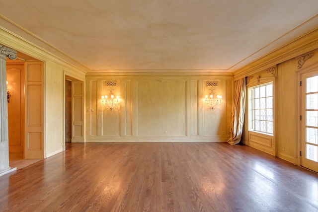 unfurnished room with decorative columns, wood-type flooring, and ornamental molding