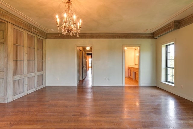 empty room featuring wood-type flooring, a chandelier, and crown molding