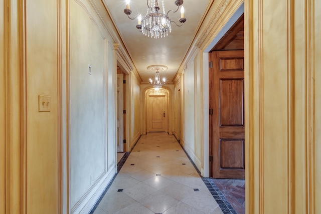 corridor with an inviting chandelier and ornamental molding