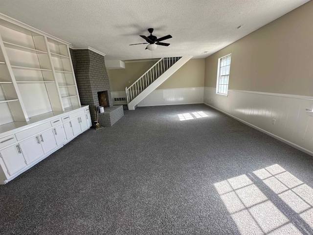 unfurnished living room featuring a textured ceiling, carpet flooring, and a brick fireplace