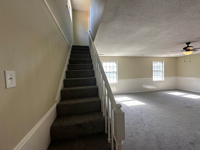 stairway featuring ceiling fan, a textured ceiling, and carpet floors